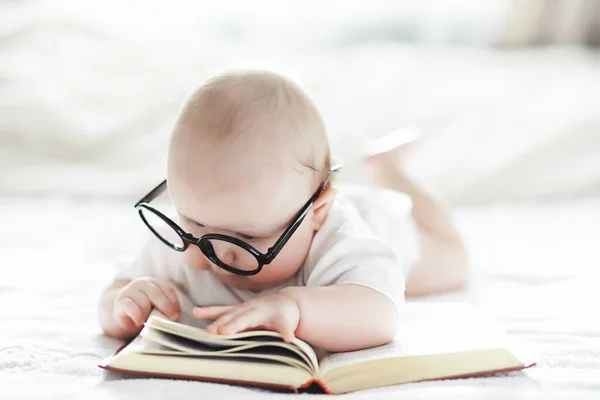 Un neonato è sdraiato su un letto morbido in occhiali . — Foto Stock