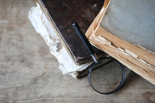 Libros antiguos sobre una mesa de madera y lupa — Foto de Stock