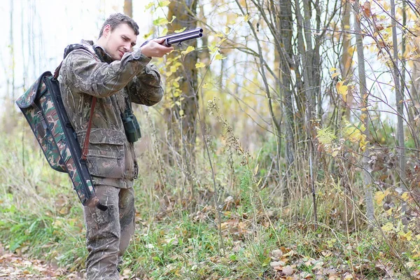 Человек в камуфляже и с оружием в лесном поясе на пружинной гуне — стоковое фото