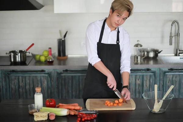 Asian cook in the kitchen prepares food in a cook suit