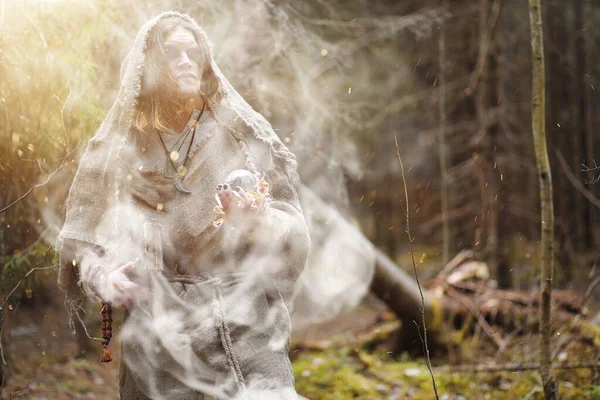 A man in a cassock spends a ritual in a dark forest — Stock Photo, Image