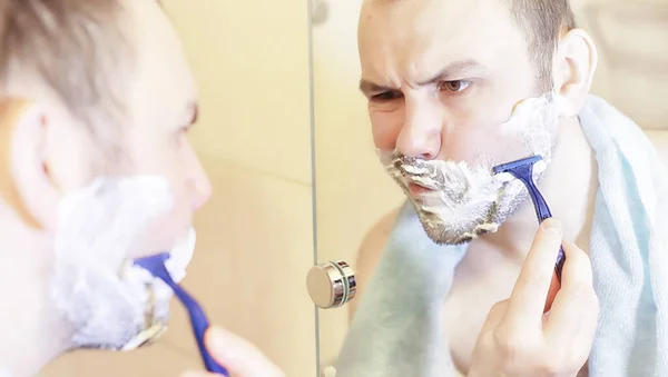 A man shaves in the bathroom in the morning — Stock Photo, Image