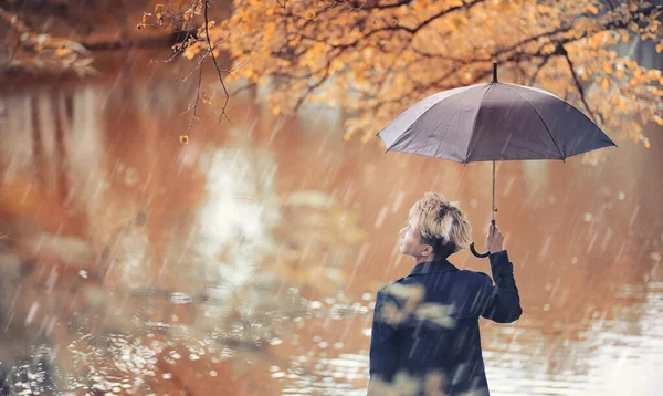 Jesienne słoty i młody człowiek z parasolem — Zdjęcie stockowe