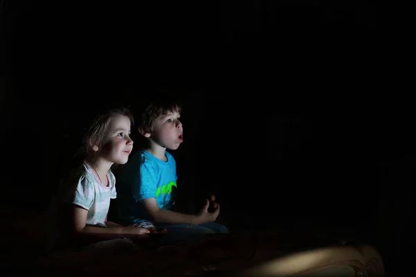 Små barn i ett mörkt rum tittar på TV — Stockfoto