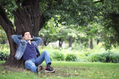 Genç bir adam öğle yemeği zamanında parkta yürür. Bir adam yürüyüşe çıktı. 