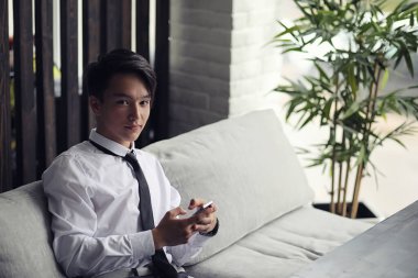 Genç Asyalı işadamı bir kafede bir ortak için bekliyor. Bu