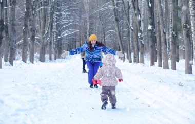 Çocuk kış parkında oynuyor ve ailesiyle eğleniyor.
