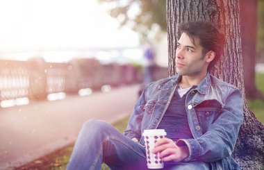 Genç bir adam öğle yemeği zamanında parkta yürür. Bir adam yürüyüşe çıktı. 