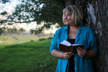 kadınla çimenlerin üzerinde kitapla Park