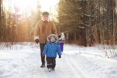 Çocuk kış parkında koşuyor ve ailesiyle eğleniyor.
