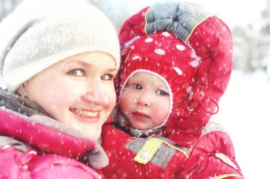 Anne ve kızı kar fırtınasında parkta.