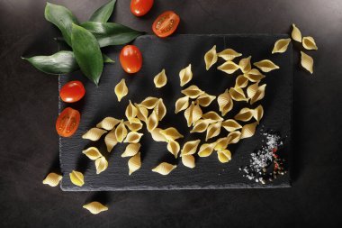 Siyah taş üzerine makarna kabukları. Allspi ile domates ve defne yaprağı