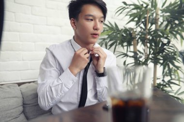 Genç Asyalı işadamı bir kafede bir ortak için bekliyor. Bu