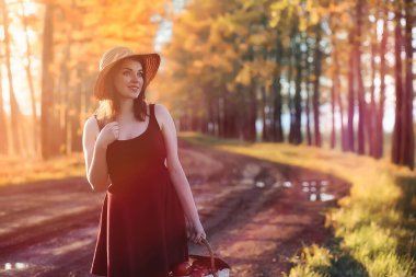 Parkta bir yürüyüş üzerinde şapkalı bir kız. Bir kızla bir sepet yürüyüş