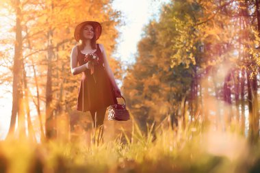 Parkta bir yürüyüş üzerinde şapkalı bir kız. Bir kızla bir sepet yürüyüş