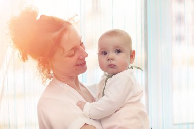 Bebek kız kollarında. Anne çocuğunu onun kollarında tutar. Küçük bir bebek ile mutlu anne