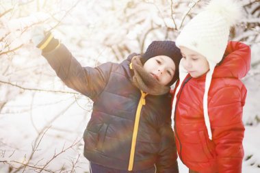Kış parkında oynayan kalın elbiseli şirin çocuklar. 
