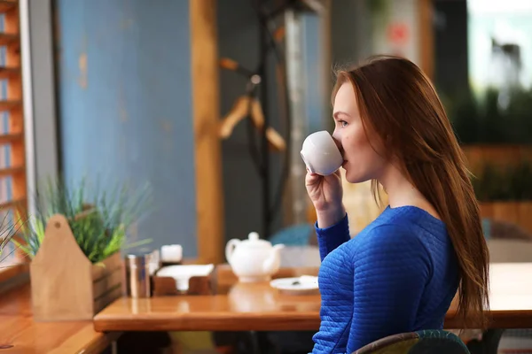 Junges Mädchen sitzt im Café und trinkt Tee — Stockfoto