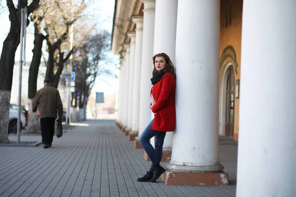 Csinos lány egy séta a város piros kabátot — Stock Fotó