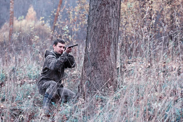 Un hombre en camuflaje y con un rifle de caza en un bosque en una sp —  Fotos de Stock