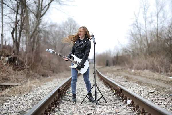 Een rock muzikant meisje in een leren jas met een gitaar — Stockfoto