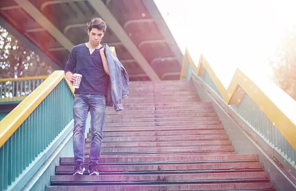 A young man walks in the park at lunch time. A man is on a walk