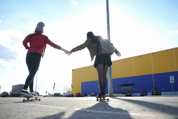 Una giovane hipster sta cavalcando uno skateboard. Ragazze amiche f — Foto Stock