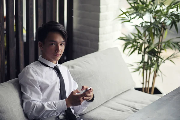 Un joven empresario asiático está esperando a un socio en un café. Bu. — Foto de Stock
