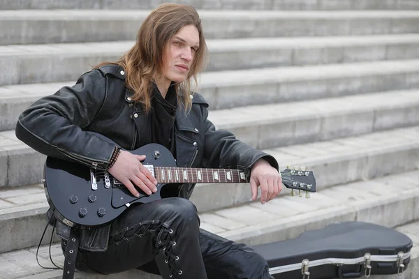 Rock guitarist på trappen. En musiker med en basguitar i en - Stock-foto