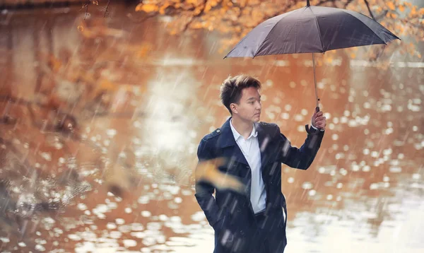 Otoño tiempo lluvioso y un joven con un paraguas —  Fotos de Stock