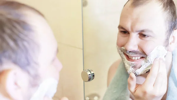 Um homem faz a barba na casa de banho pela manhã — Fotografia de Stock