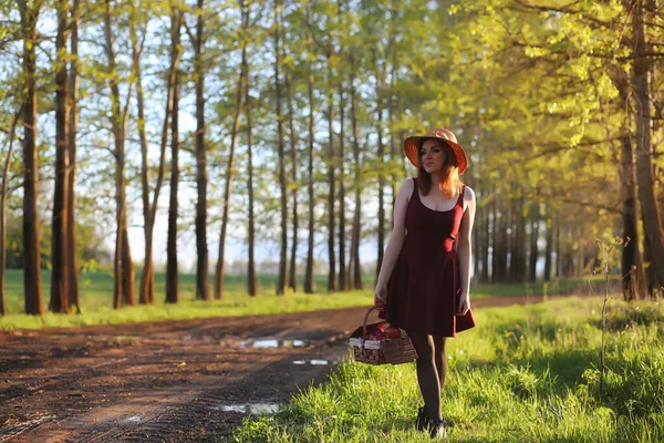 Ein Mädchen mit Hut bei einem Spaziergang im Park. ein Mädchen mit einem Korblauf — Stockfoto