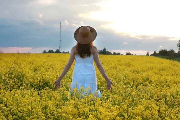 Chica en sombrero de paja en un campo de flores amarillas floreciendo — Foto de Stock