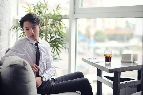 Un joven empresario asiático está esperando a un socio en un café. Bu. — Foto de Stock