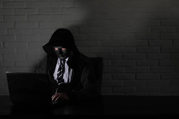 Hacker em máscara preta e capuz na mesa — Fotografia de Stock