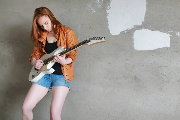 Fiatal vörös hajú lány egy elektromos gitár. Rock zenész lány — Stock Fotó