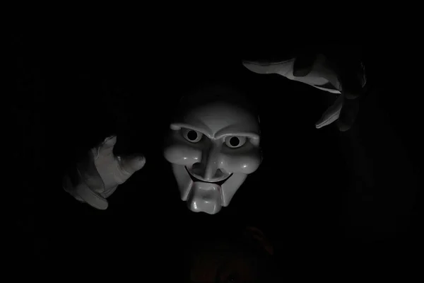 White scary mask on a black background with whites hand. — Stock Photo, Image