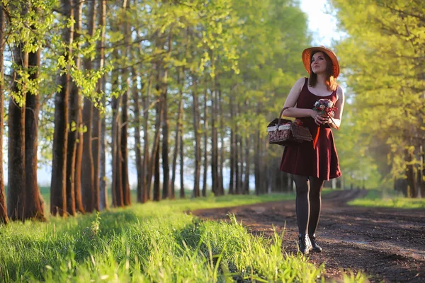 Dívka v klobouku na procházce v parku. Dívka s procházku košík — Stock fotografie