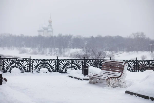 Winter city landscape. Winter park covered with snow. A bench un