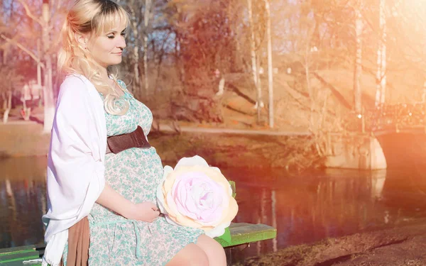 Schwangere Mädchen bei einem Spaziergang im Park. Mädchen mit einem Bauch in der Hand — Stockfoto