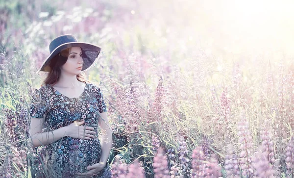 Gravid flicka i ett fält med blommor — Stockfoto