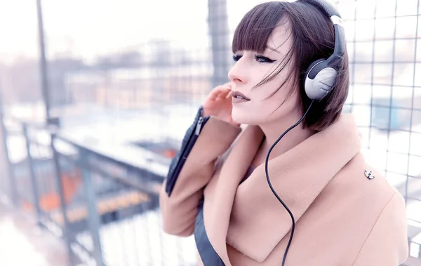 Pige i hovedtelefoner lytter til musik udendørs - Stock-foto