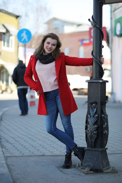 Chica bonita en un paseo en abrigo rojo en la ciudad — Foto de Stock