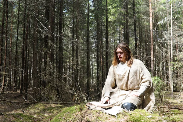 Um homem numa batina passa um ritual numa floresta escura. — Fotografia de Stock