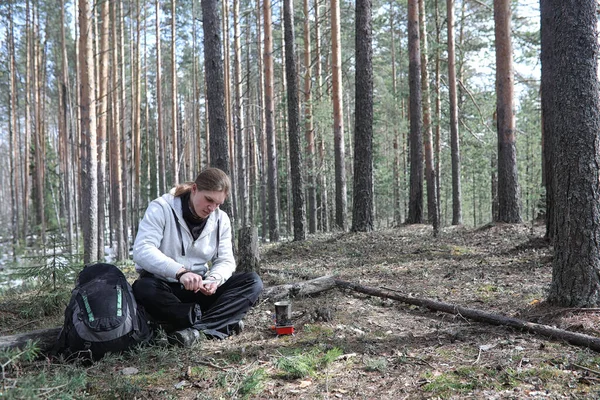 A man in a campaign drinks tea. A young traveler in the woods ca