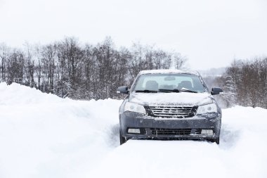 Bir karla kaplı yolda araba duruyor