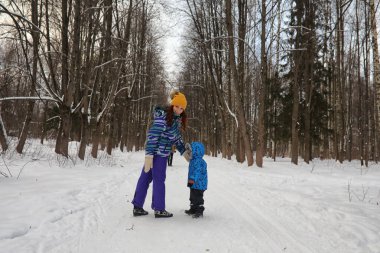 Ailesi olan bir çocuk kış parkında eğleniyor.