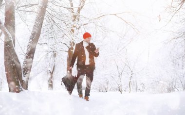 Parkta yürüyen bir adam. Genç adam kışın karla kaplı