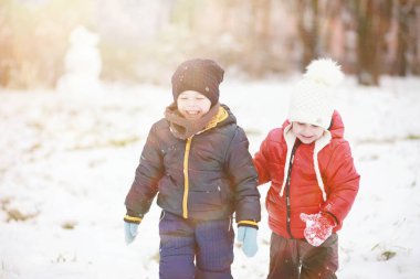 Kış parkında oynayan kalın elbiseli şirin çocuklar. 