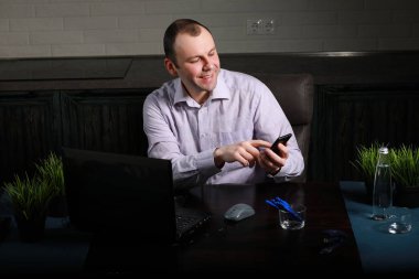 Masada oturan ve dizüstü bilgisayarda çalışan adam